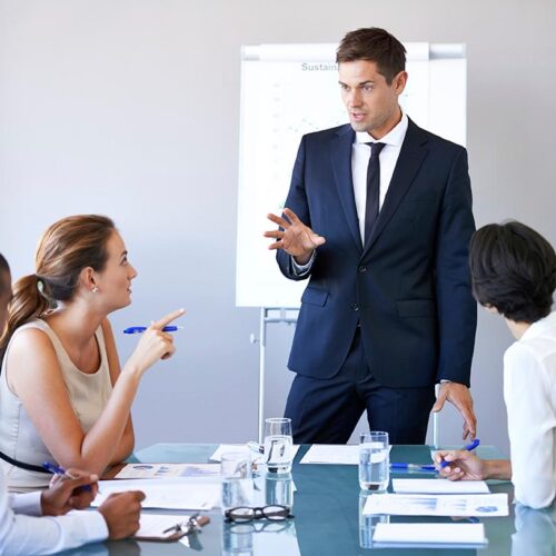 Man in blue suit presenting to small group