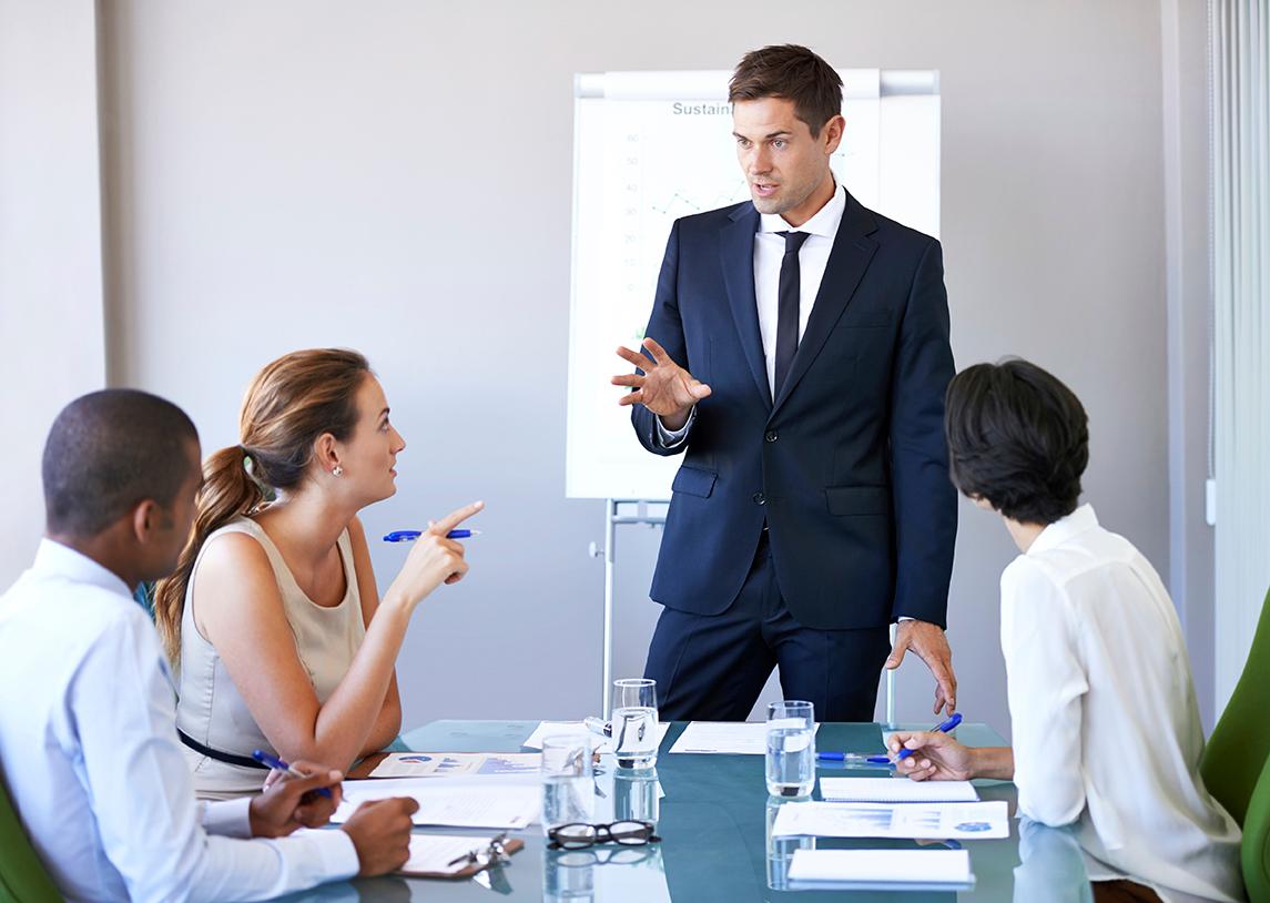 Man in blue suit presenting to small group